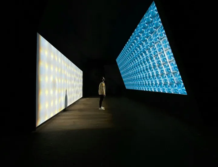 A visitor standing between two illuminated digital displays