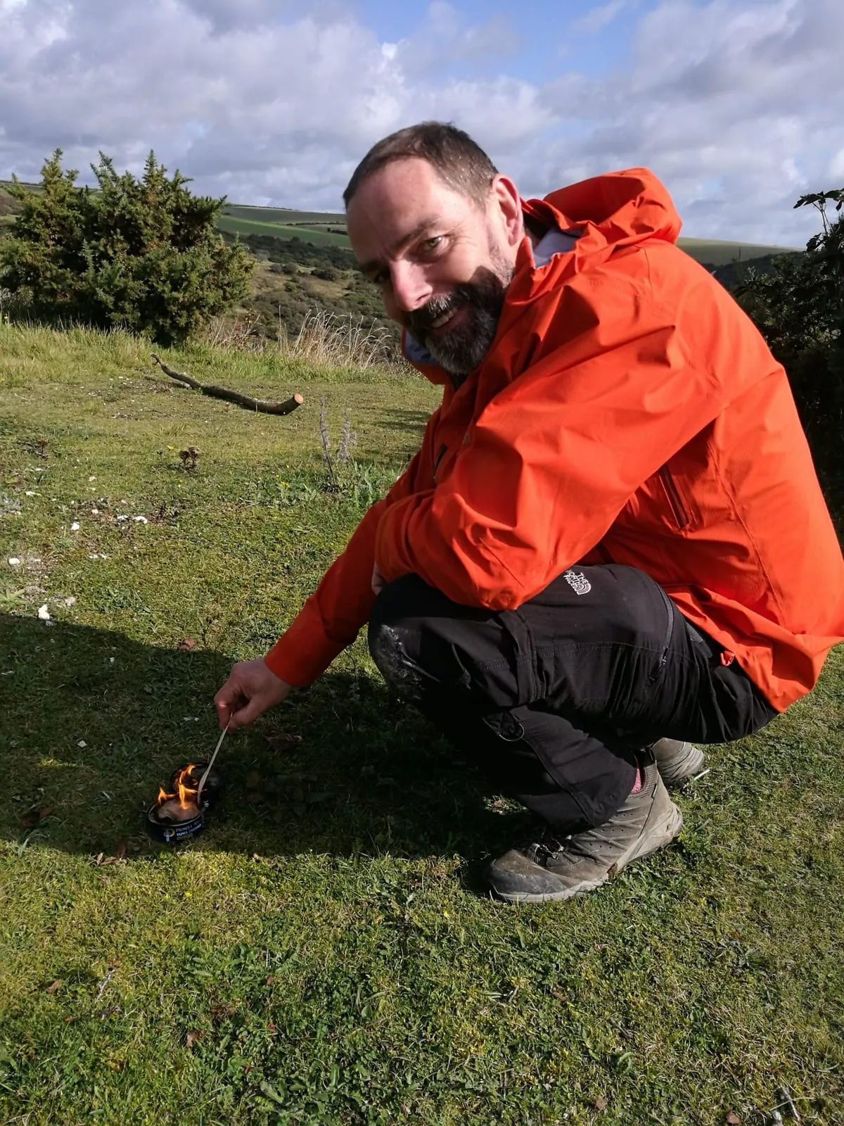 A team member carefully lighting a small camp stove