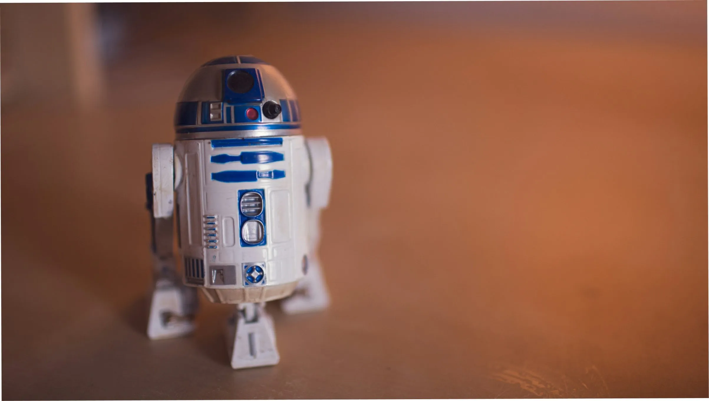 An R2-D2 model against a warm orange background
