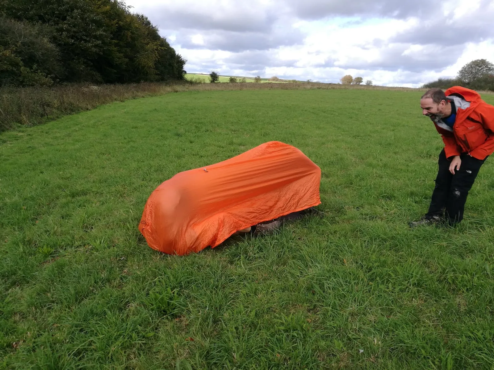An orange survival bag shelter on grass