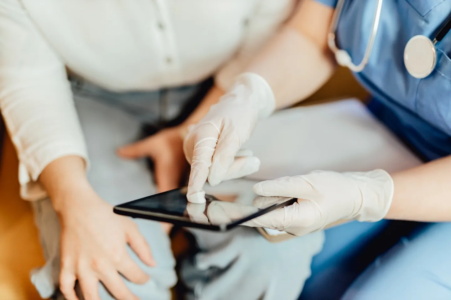 A clinician using a tablet beside a patient