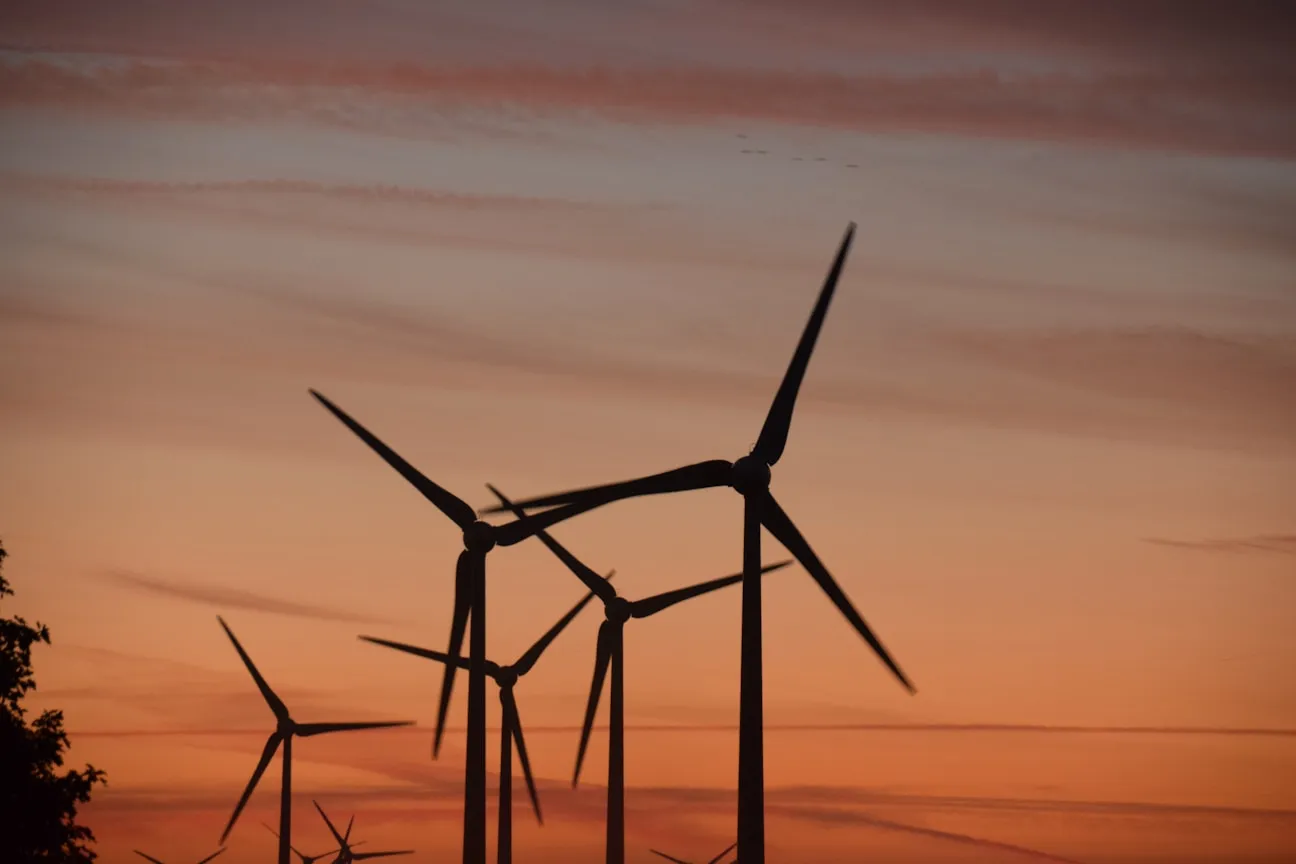 Wind turbines silhouetted against a sunset