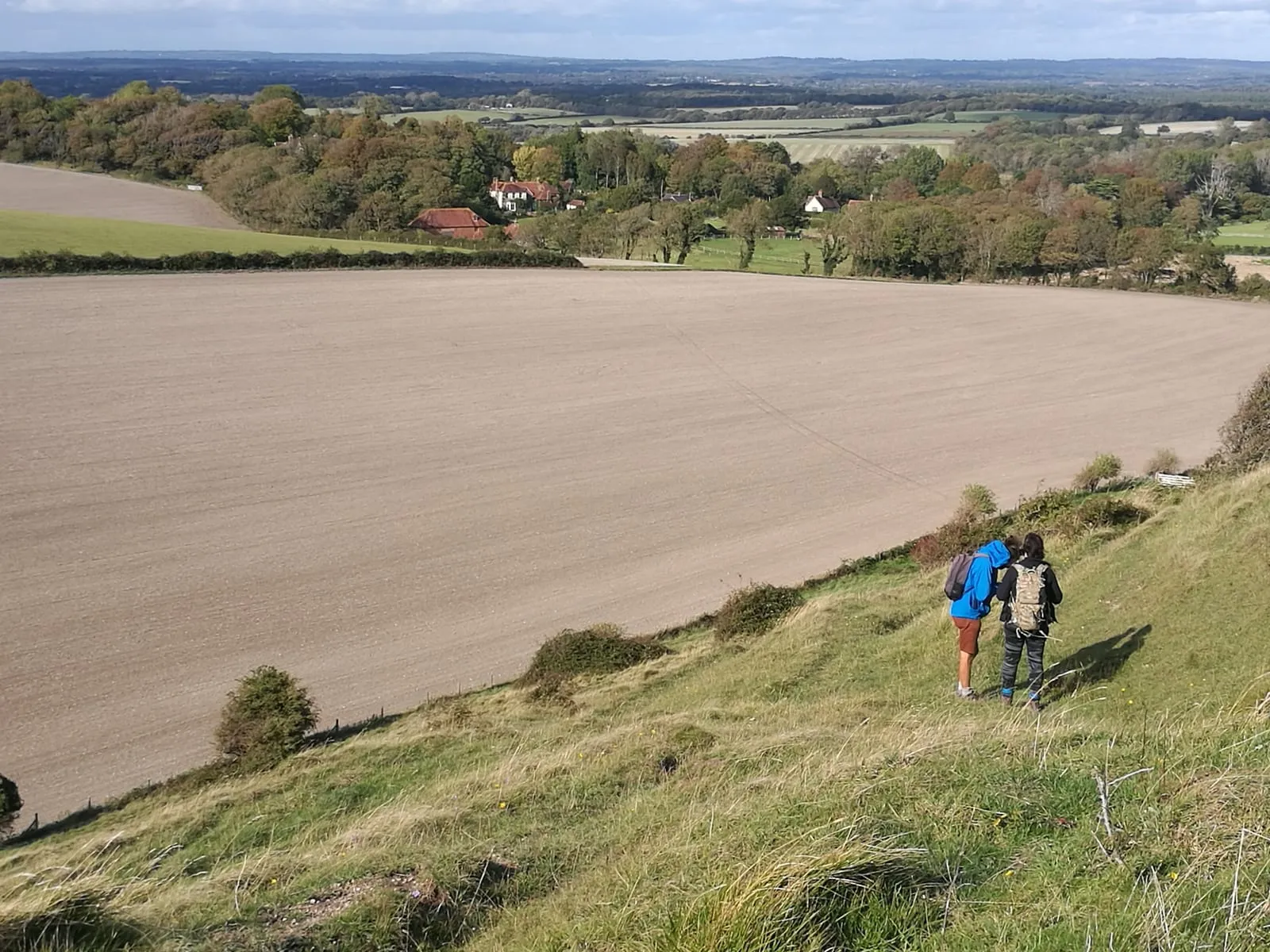 Two walkers descending a South Downs hillside